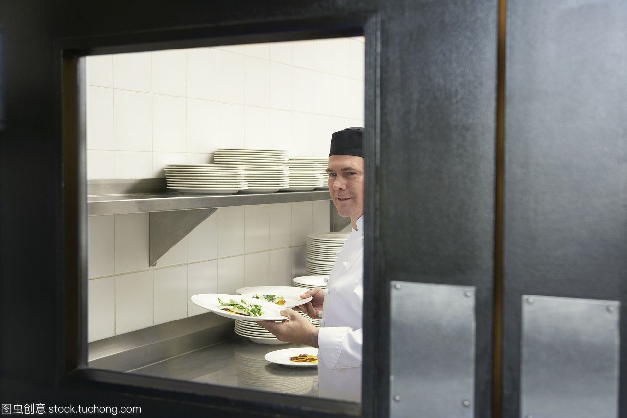 专业厨房中的热情服务 微笑厨师与精美正餐